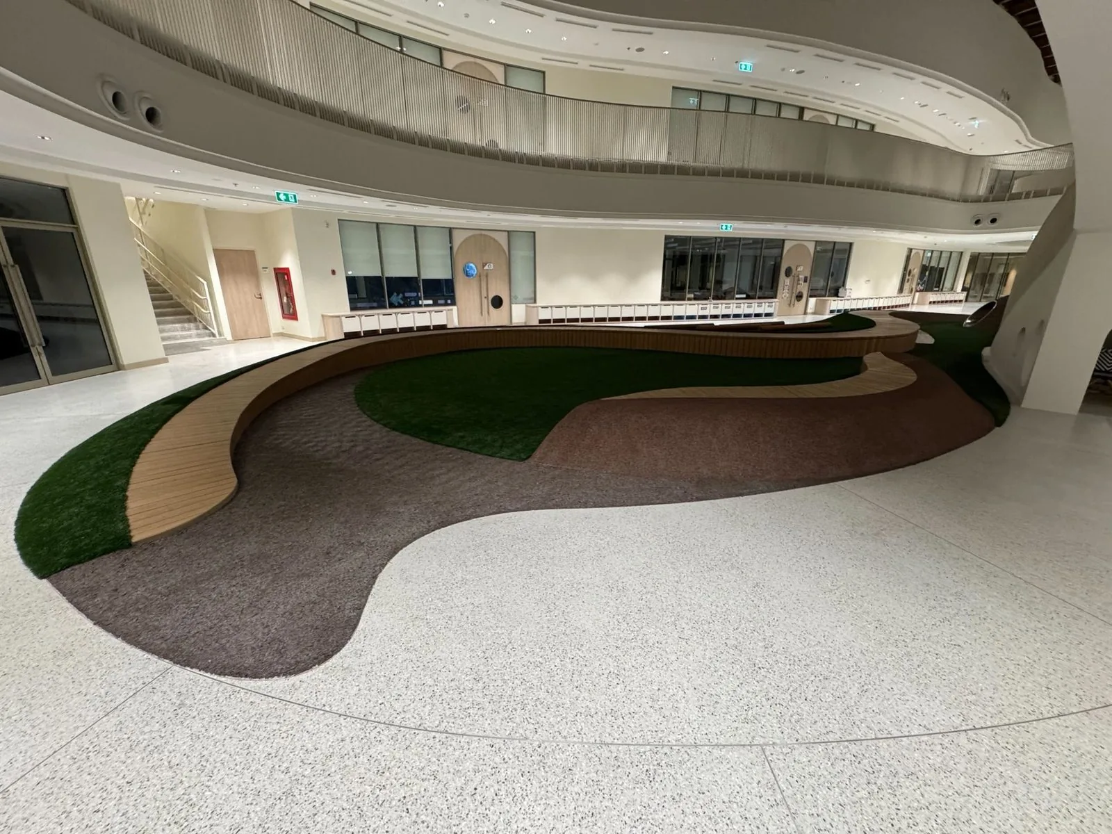 The Forest meadow — artificial-grass mounds and a timber boardwalk winding through the atrium